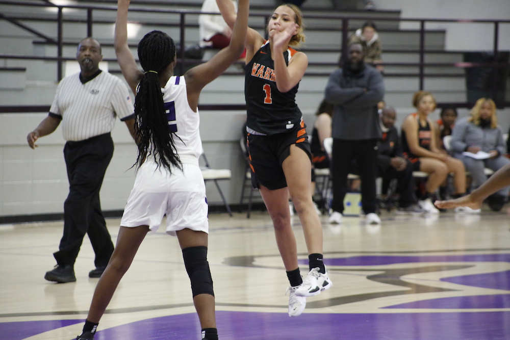 A girl in black jersey playing basketball on court.