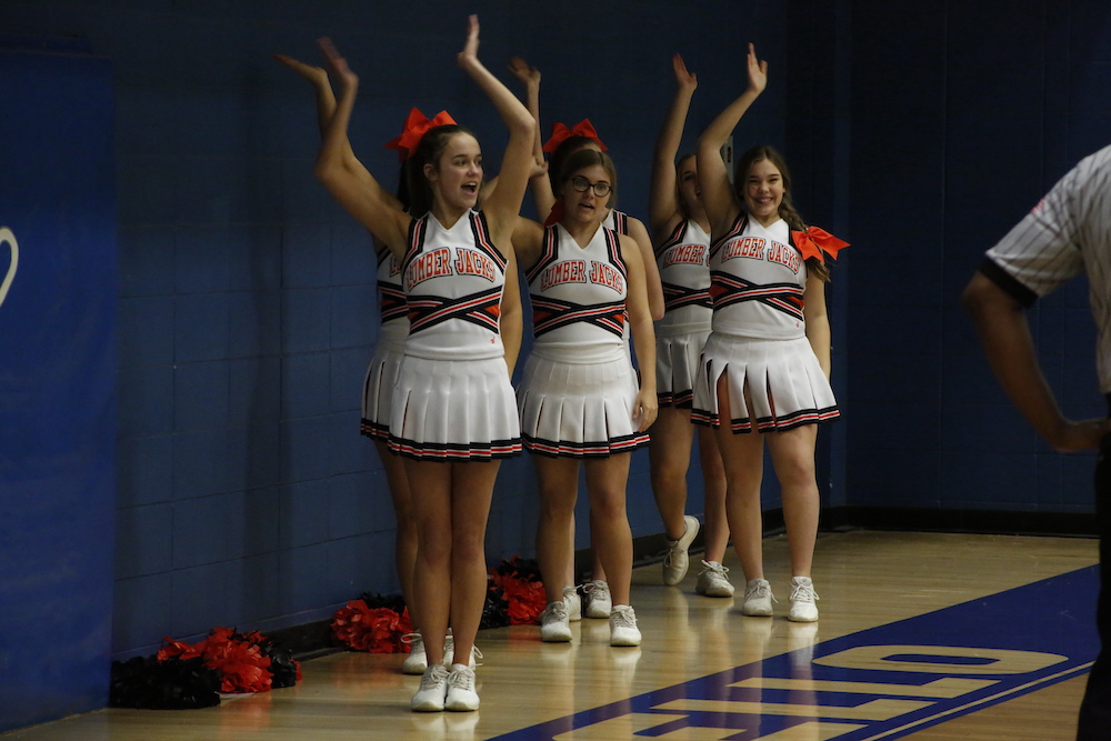 A group of cheerleaders standing on top of a basketball court.