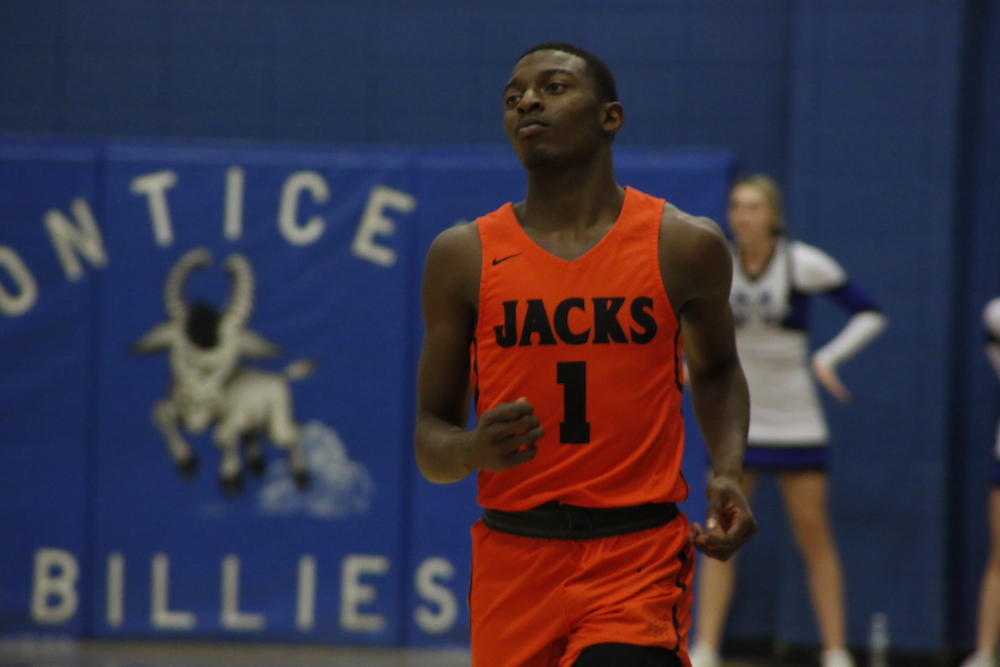 A basketball player in an orange uniform is running.