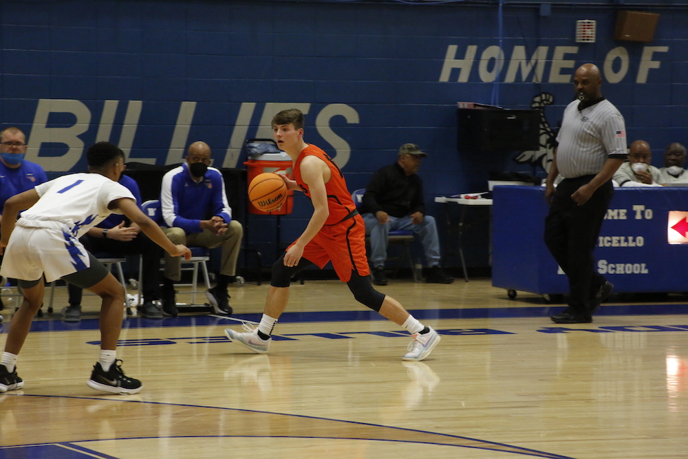 A man in an orange and white uniform playing basketball.