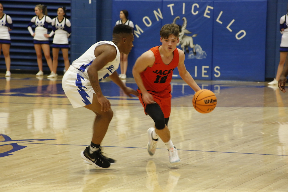 A boy dribbles the basketball while another looks on.