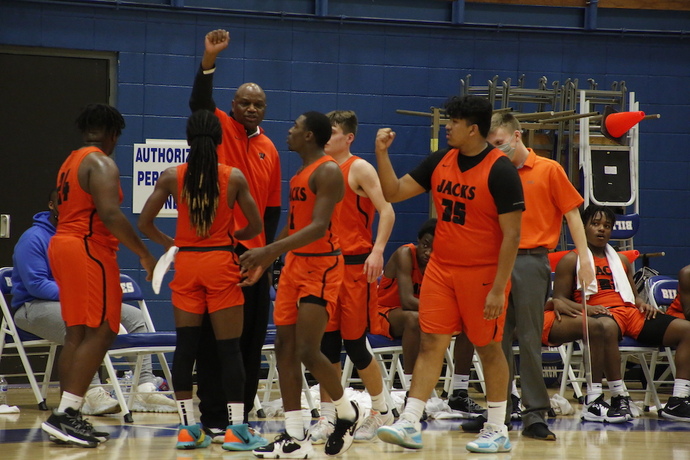 A group of men in orange shirts and shorts playing basketball.
