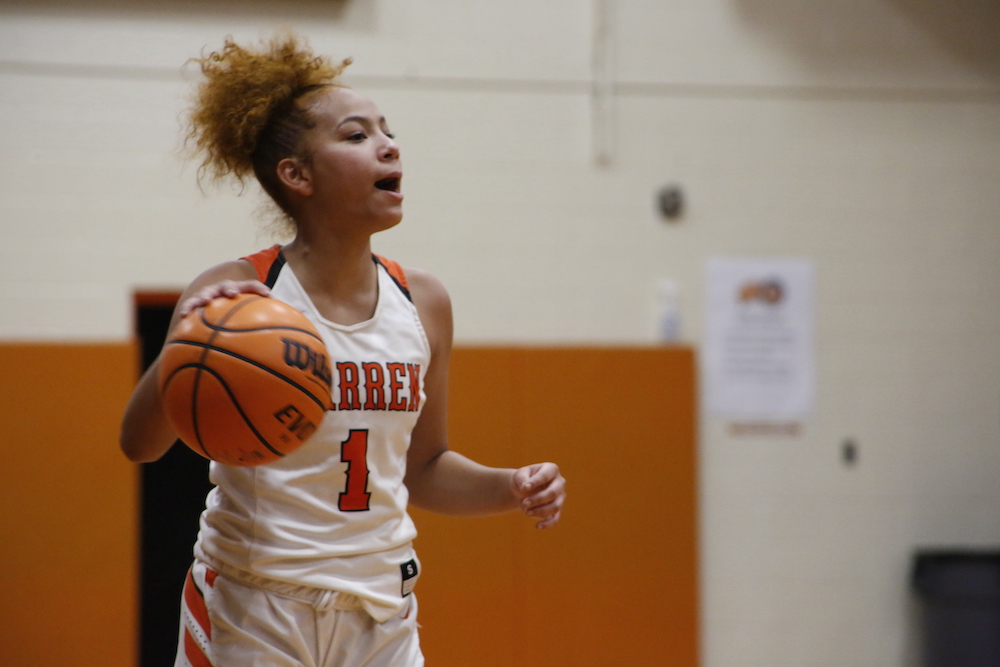 A girl holding onto a basketball in the air