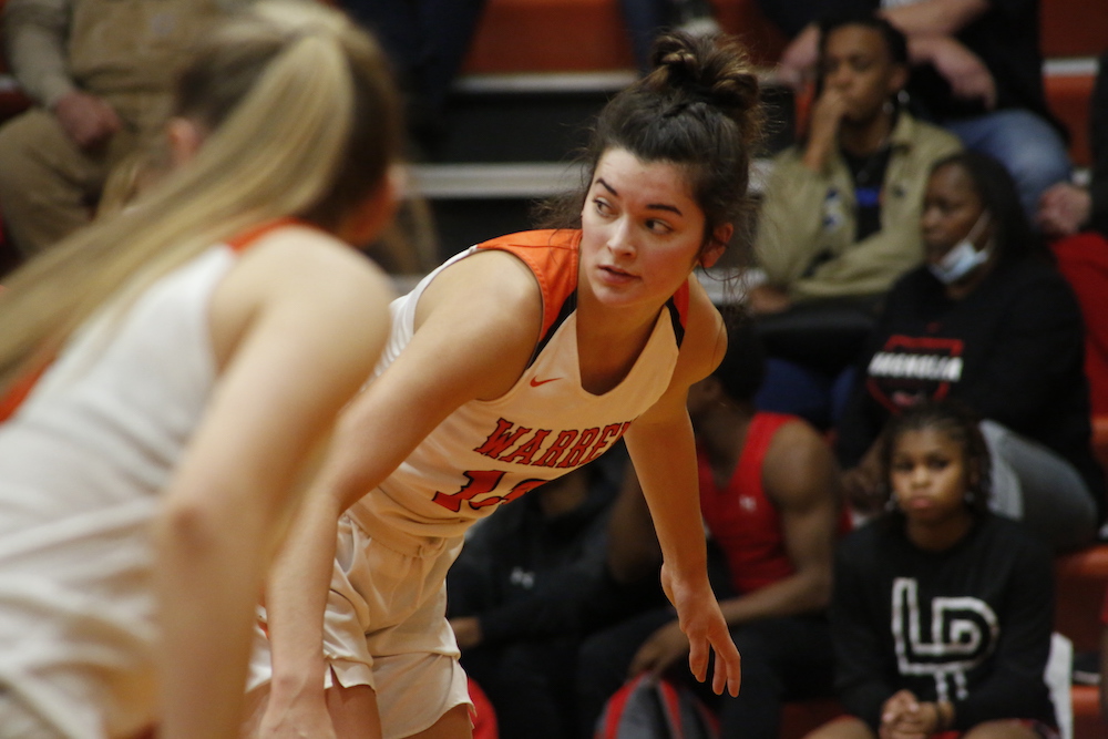 A girl in orange and white playing basketball.