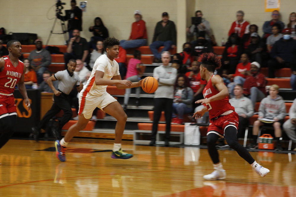 Two men playing basketball on a court with spectators watching.