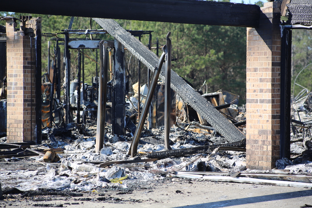 A fire destroyed building with debris scattered around it.