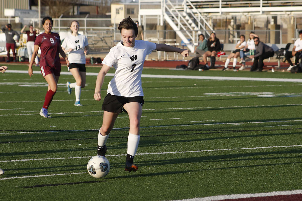 A girl is playing soccer on the field