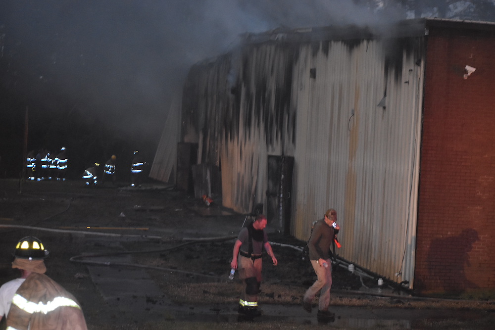 Two people walking in front of a building on fire.