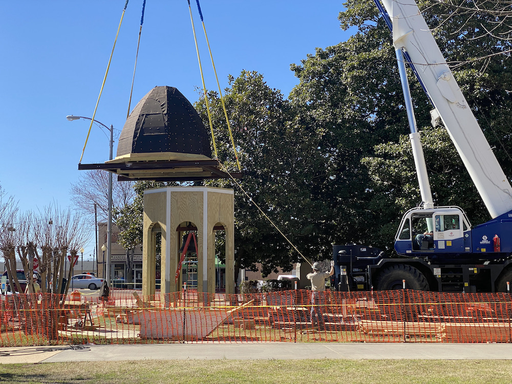 A crane is lifting the top of a building.