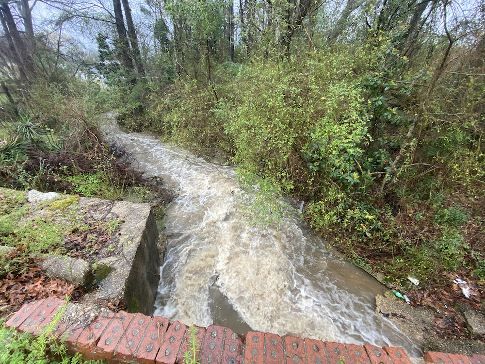 A stream of water flowing over the side of a brick wall.