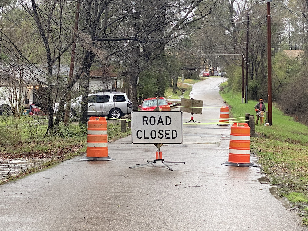 A road closed sign sitting on the side of a street.