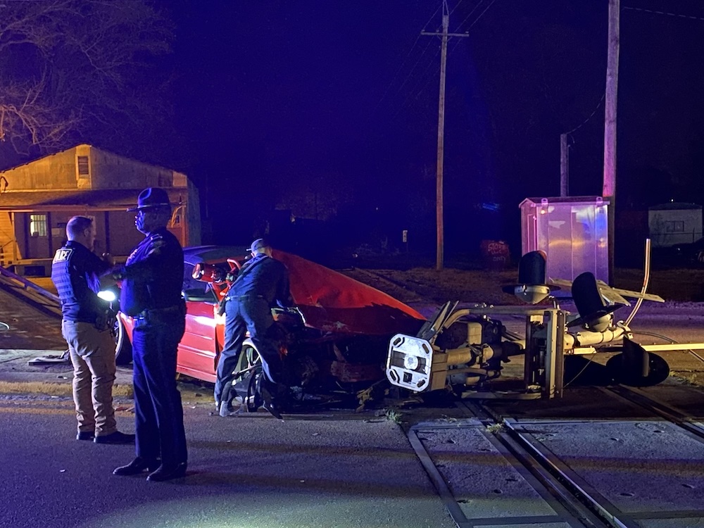 A police officer standing next to a car that is on the side of a road.