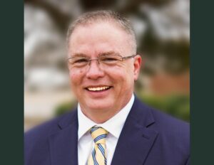 A man in a suit and tie smiling for the camera.