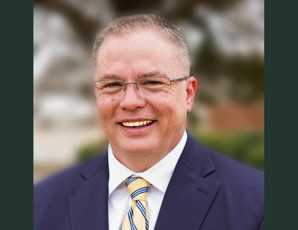 A man in a suit and tie smiling for the camera.
