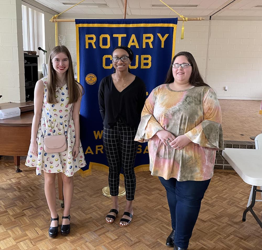 Three people standing in front of a banner.
