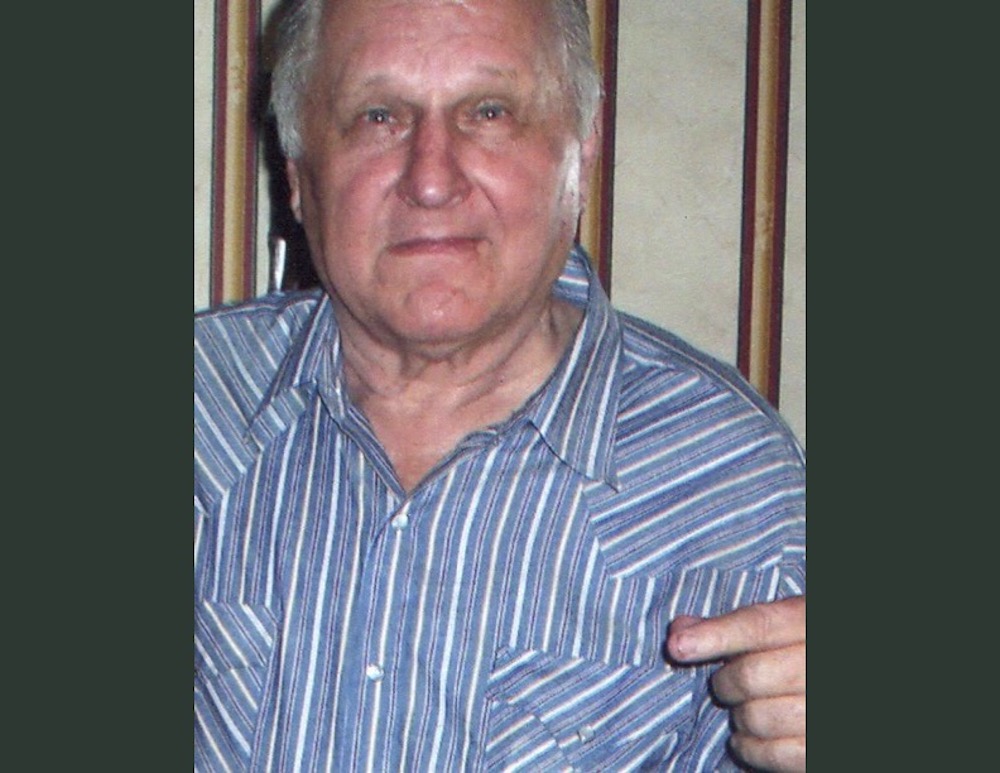 A man in striped shirt pointing at his face.