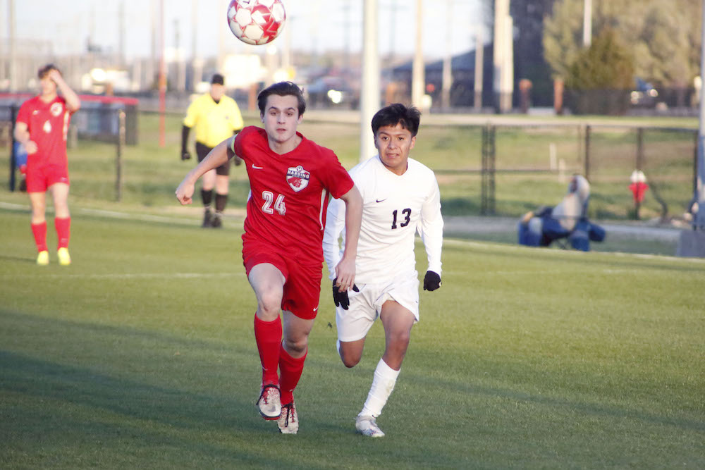 Two young men playing soccer on a field.