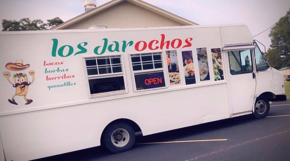 A white food truck with open doors on the side.