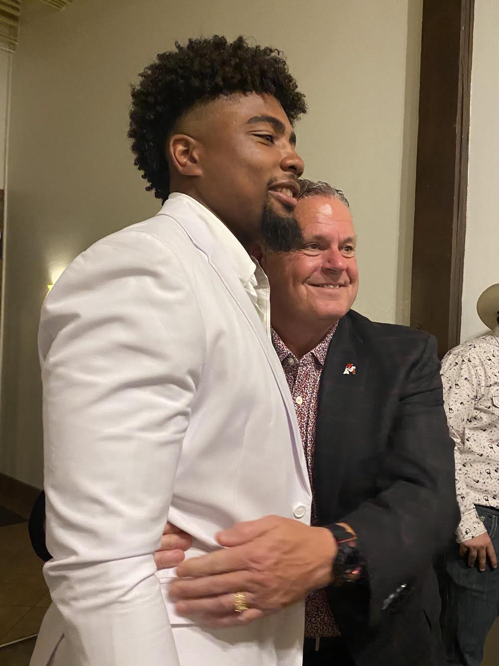 A man in suit and tie hugging another man.
