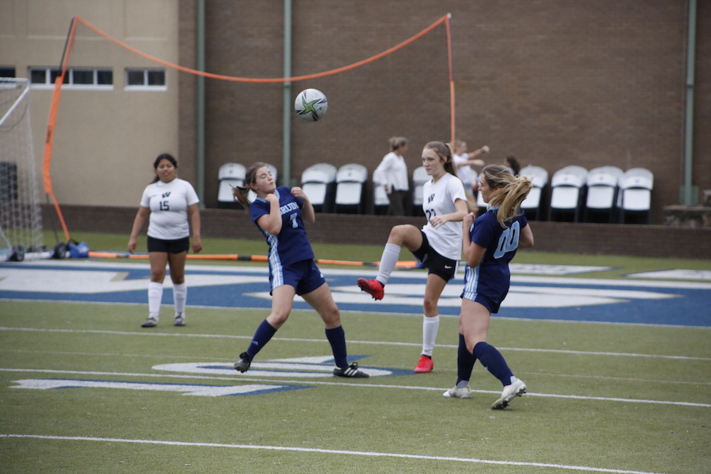 A group of girls playing soccer on the field.