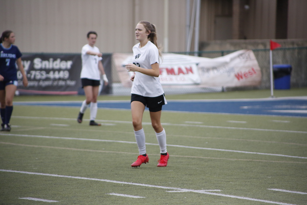 A girl is playing soccer on the field