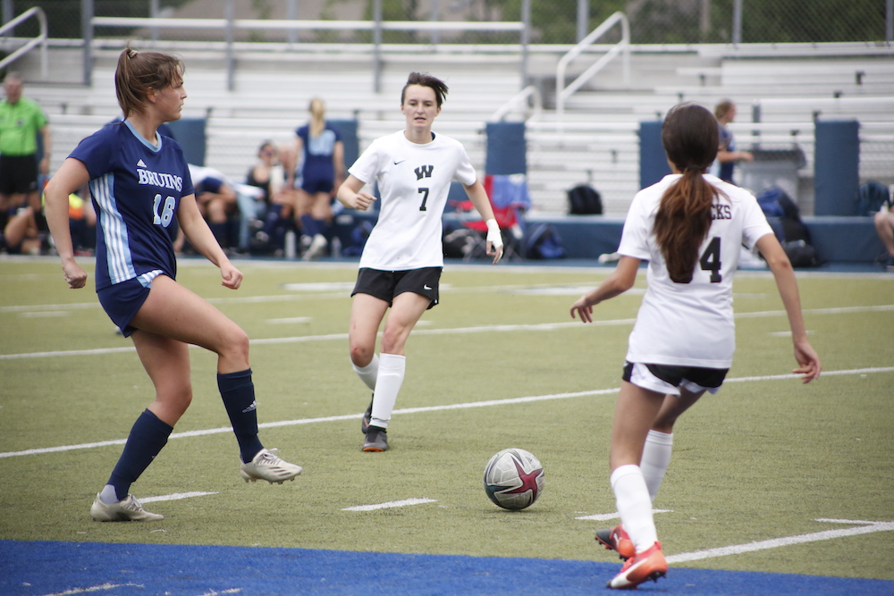 A group of girls playing soccer on the field.