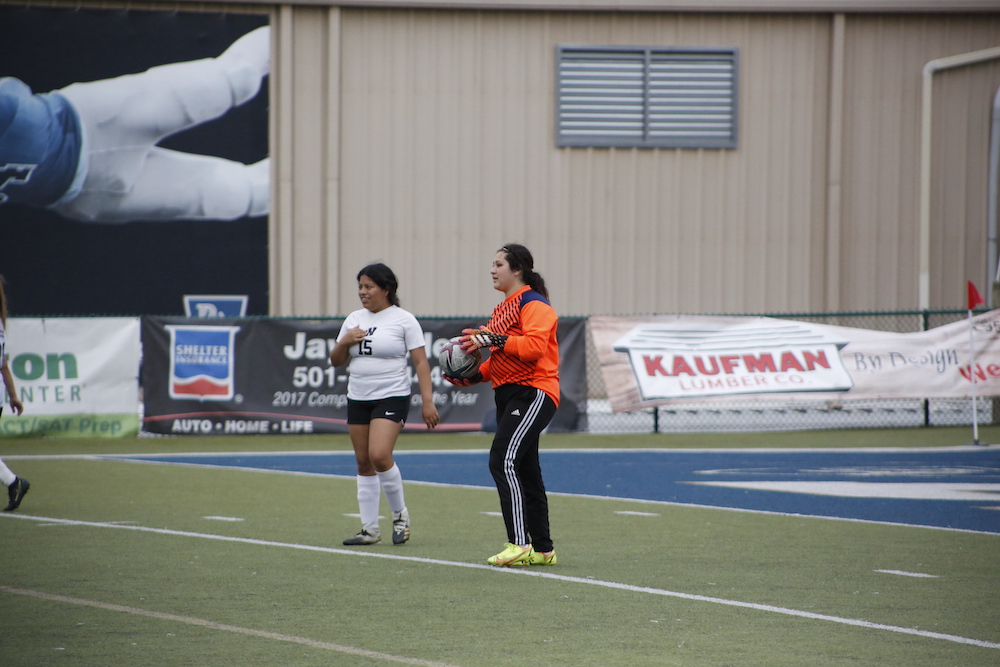 Two women standing on a field with soccer balls.