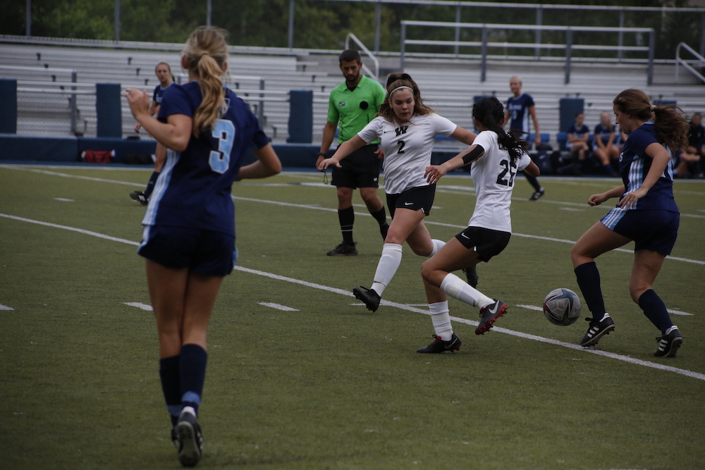 A group of girls playing soccer on the field.