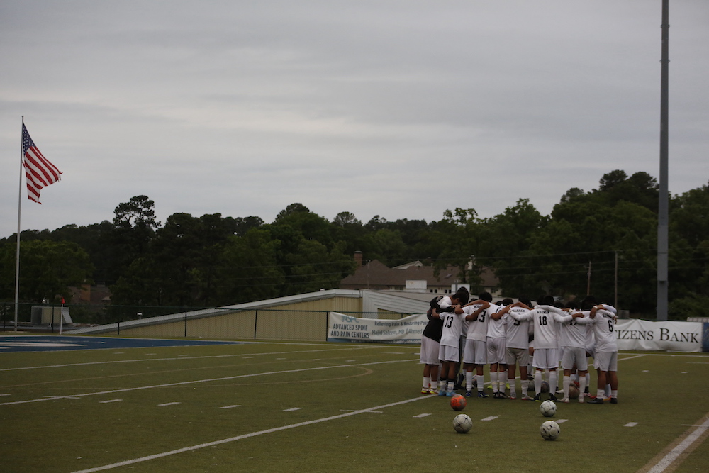 A group of people standing on top of a soccer field.