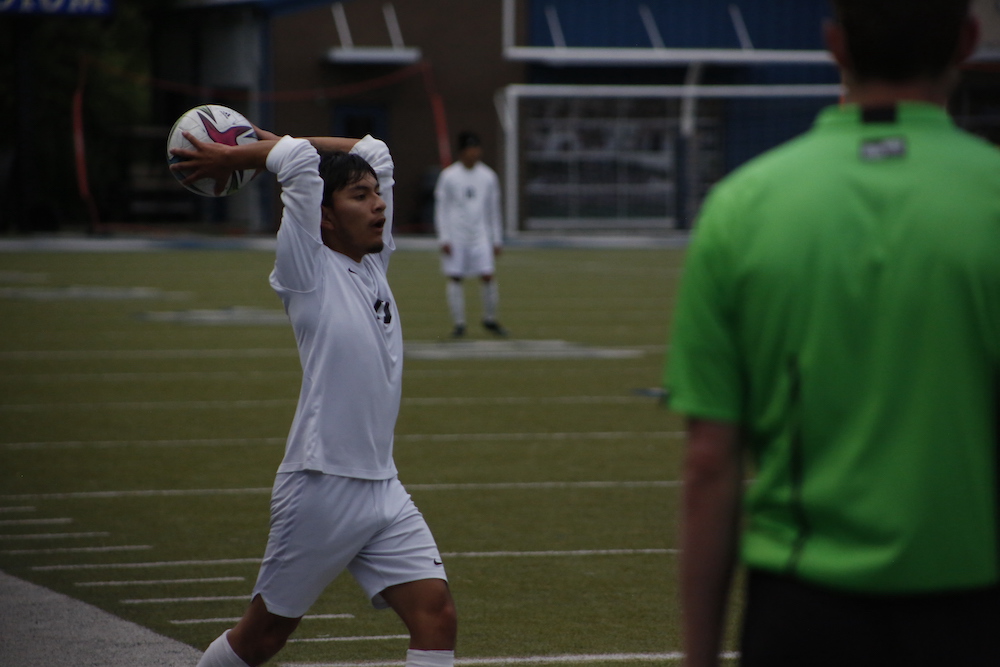 A soccer player is holding his arm up to hit the ball.