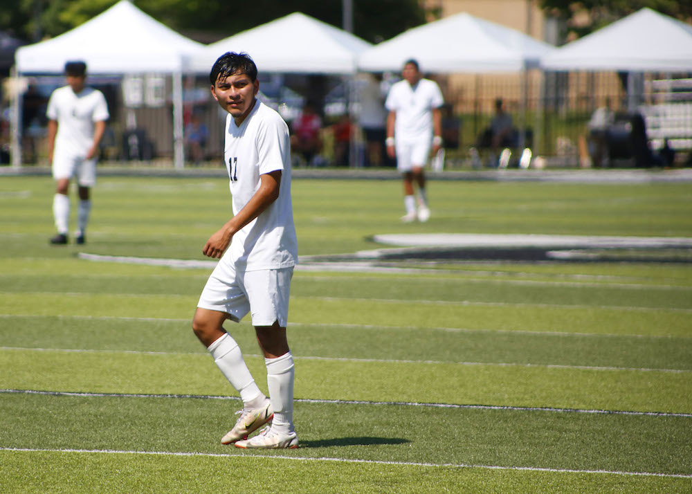 A young man in white is playing soccer.