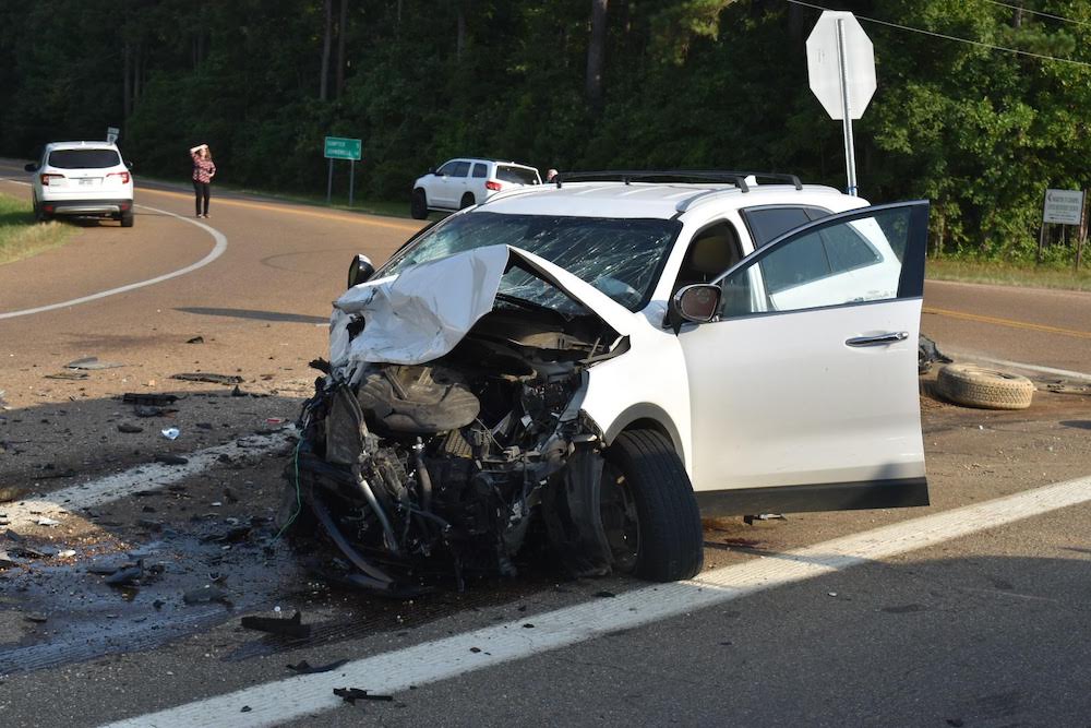A white car that has been smashed in the road.