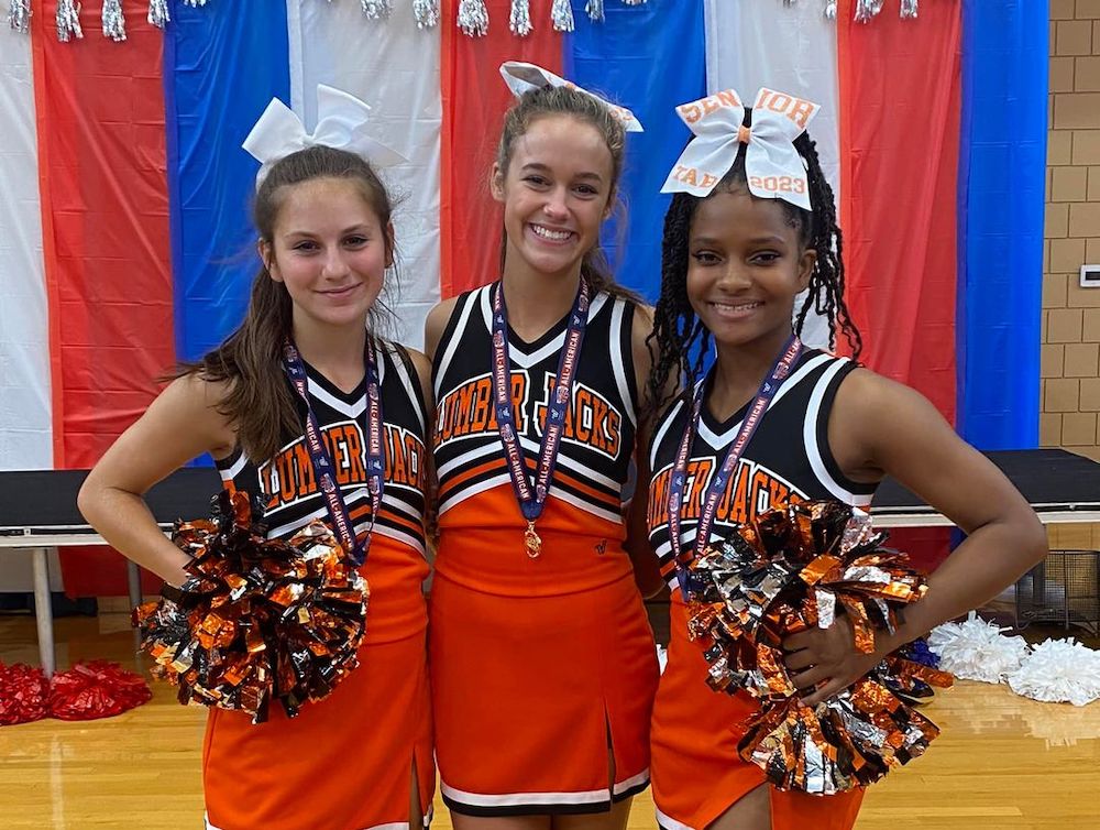Three young cheerleaders posing for a picture.