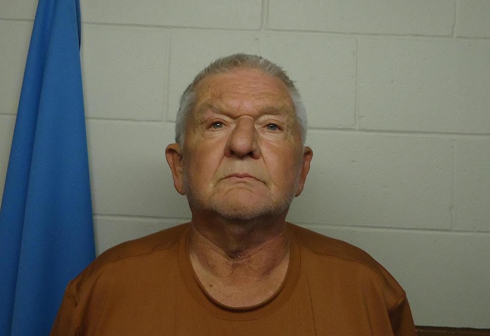 A man with gray hair and a brown shirt.
