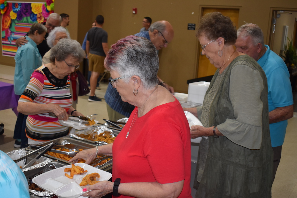 A group of people standing around plates with food.