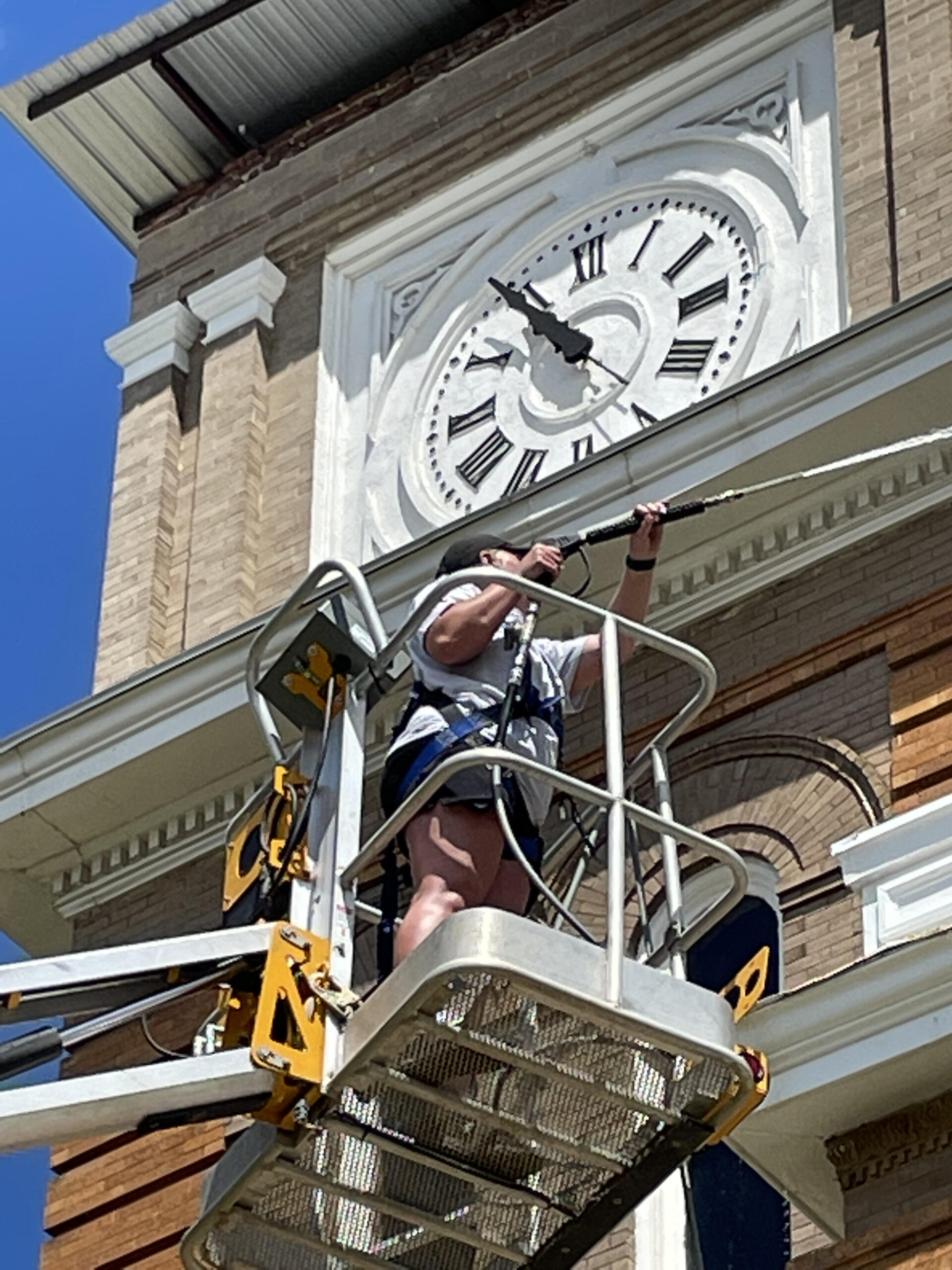 A man on a crane working on the side of a building.