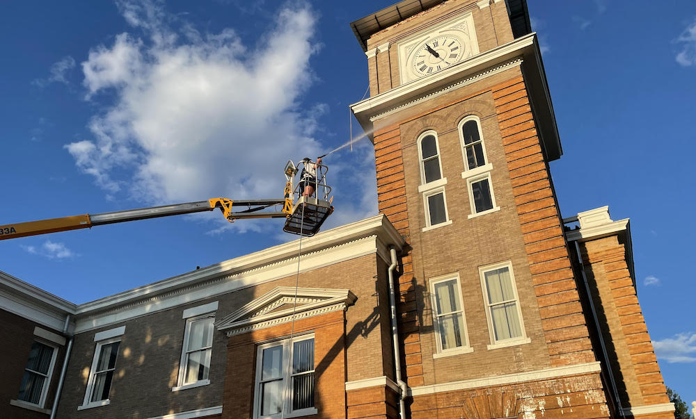 A man on a crane is working on the clock tower.