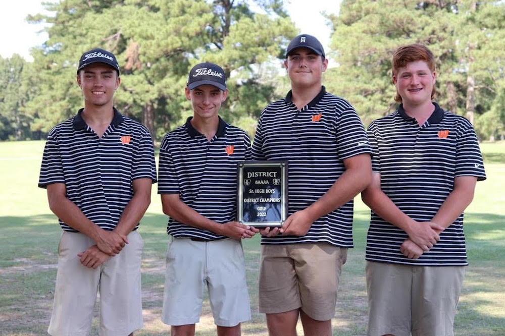 A group of men holding a plaque in front of trees.