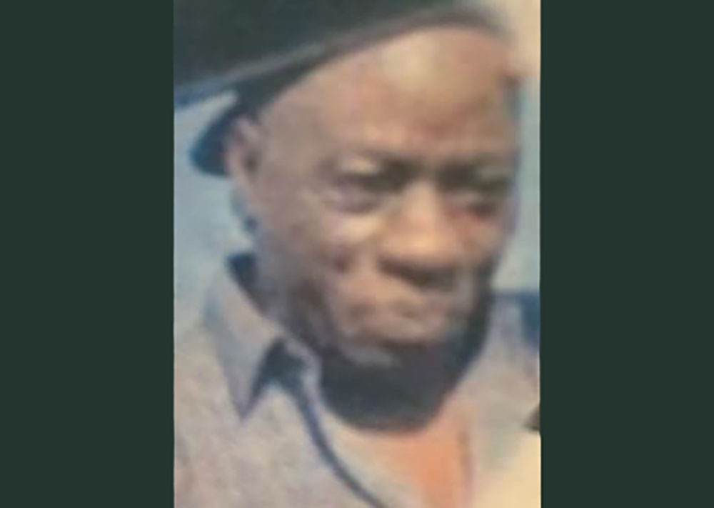 A man with a hat on and wearing glasses.