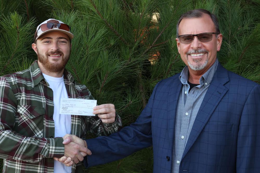 A man holding a cheque for $ 1 0, 0 0 0