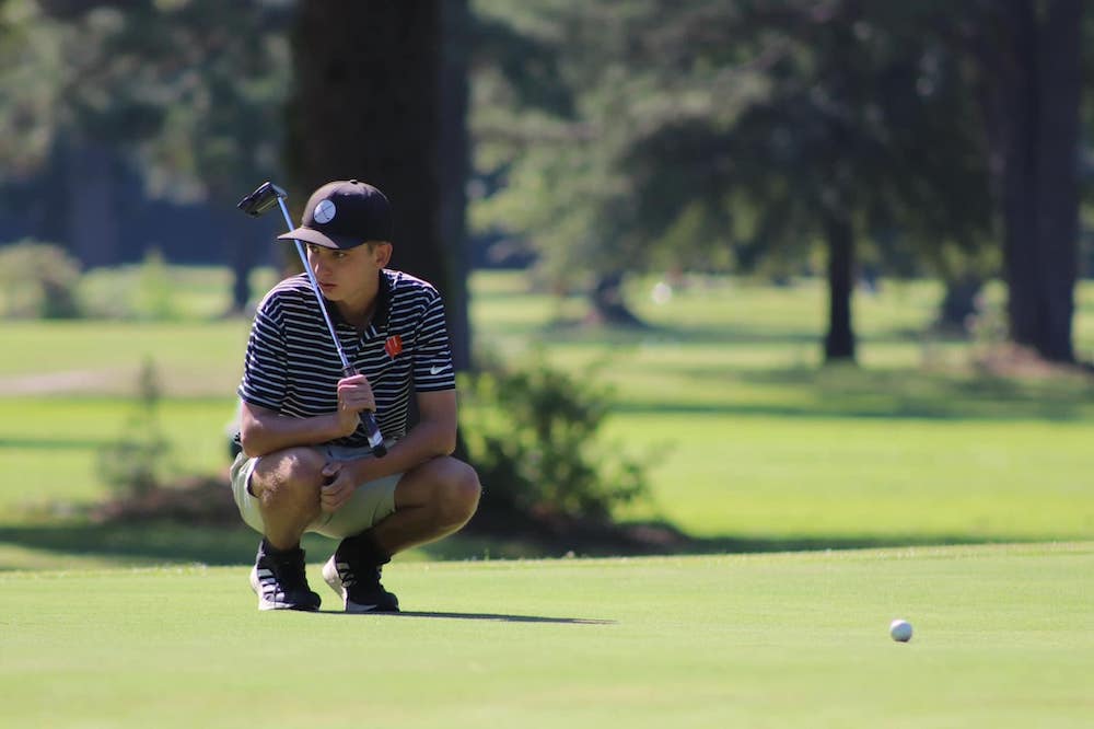 A man crouches down to look at the ball.