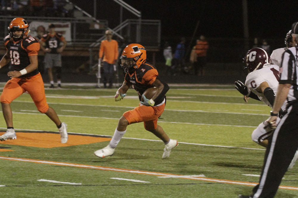 A football player running with the ball in his hand.
