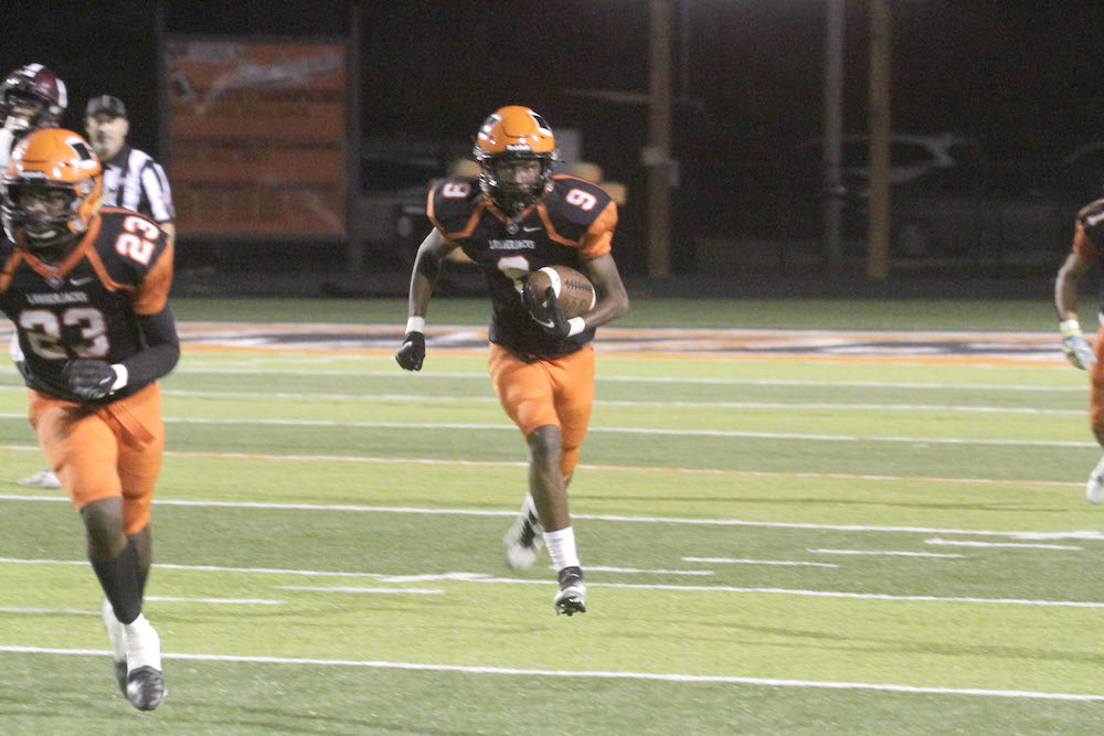 A football player running on the field with a ball