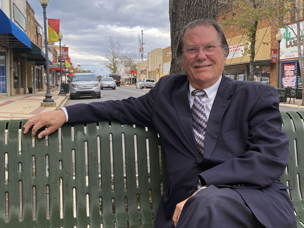 A man in a suit and tie sitting on a bench.