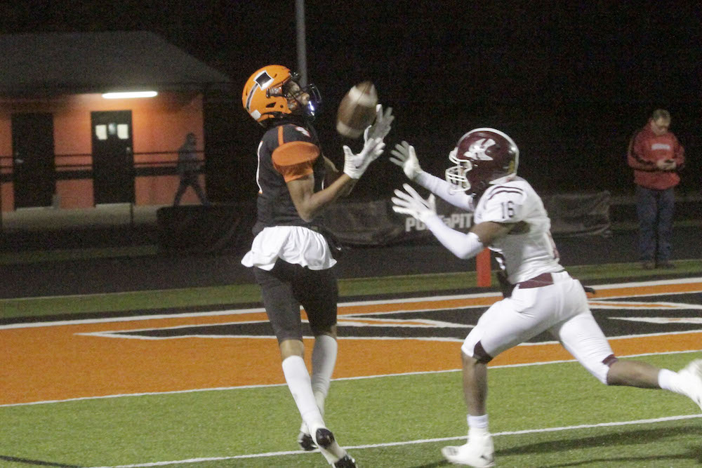 A football player catches the ball while another plays.