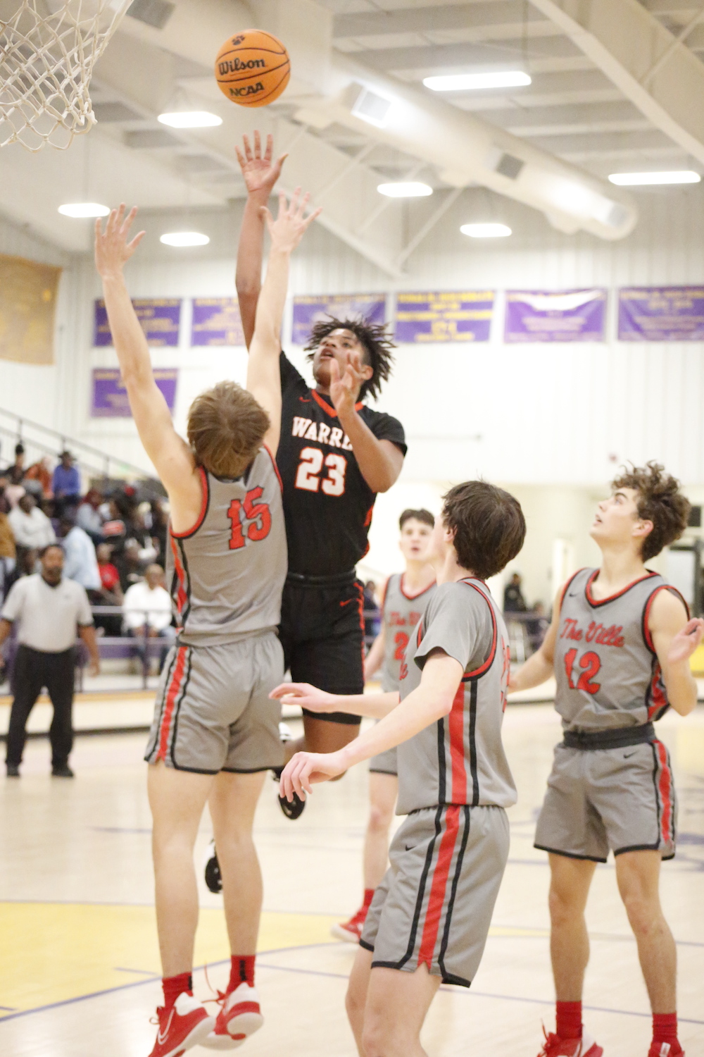 A group of young men playing basketball on a court.