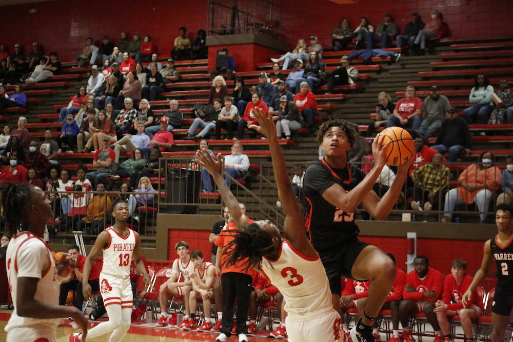 A group of people playing basketball in front of an audience.