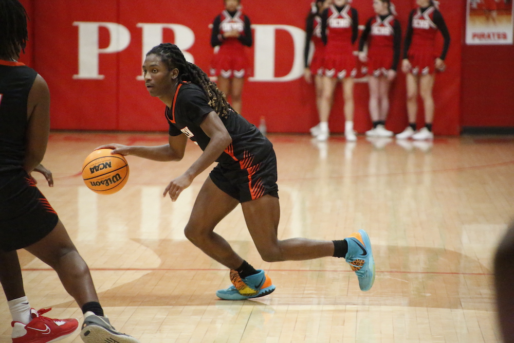 A girl dribbles the basketball on a court.