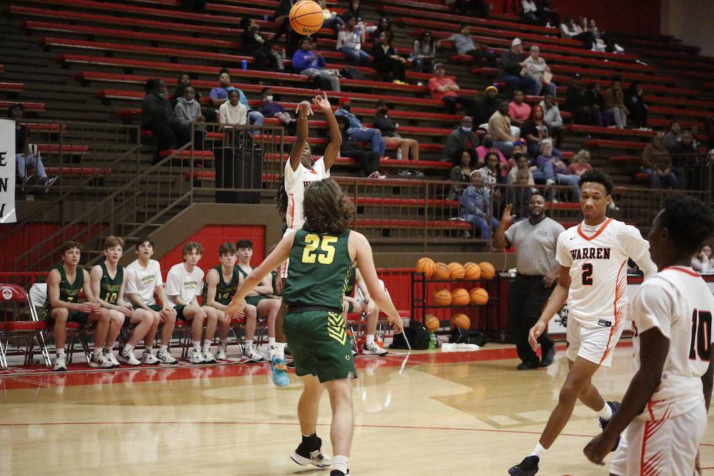 A group of people playing basketball in front of an audience.