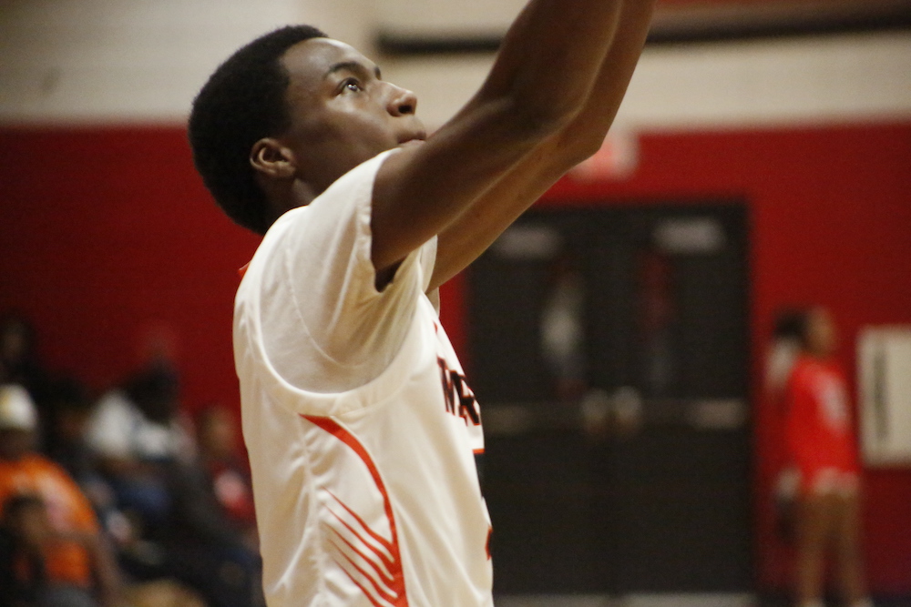 A man in white shirt playing basketball on court.